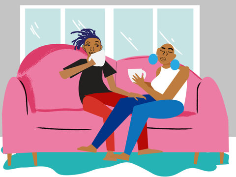 Gay couple having coffee on the couch in front of a window