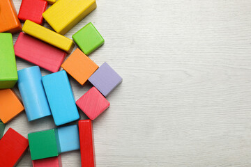 Colorful building blocks on wooden floor, flat lay. Space for text