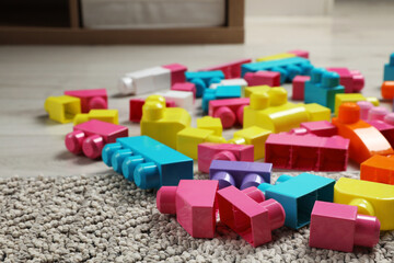 Colorful plastic building blocks on floor indoors, space for text