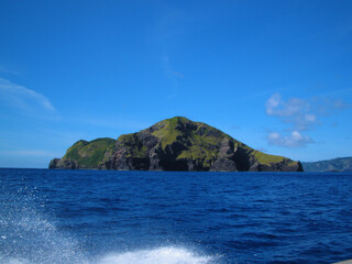 Fototapeta na wymiar 波しぶきの立つ美しい海と岩山の風景