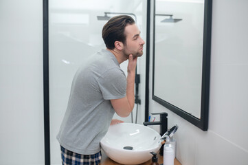 Dark-haired man looking at his reflection in a mirror