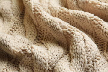 Beige knitted fabric with beautiful pattern as background, closeup