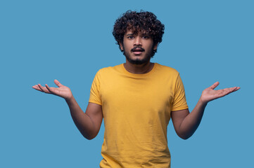 Puzzled guy with curly hair showing his uncertaintyPuzzled guy with curly hair showing his...
