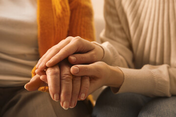Young and elderly women holding hands together, closeup