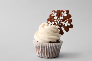Tasty Christmas cupcake with gingerbread cookie on light background
