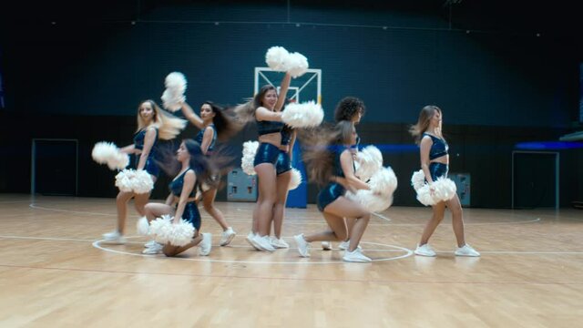 HANDHELD Female cheerleaders team performing a dance during a basketball game intermission