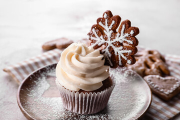 Plate of tasty Christmas cupcake with gingerbread cookie on table