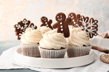 Tray of tasty Christmas cupcakes with gingerbread cookies on table