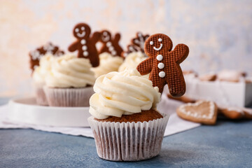 Tasty Christmas cupcakes with gingerbread cookies on table