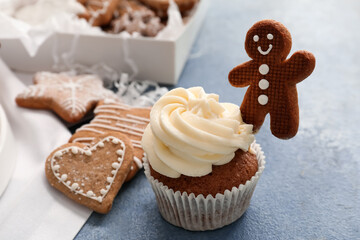 Tasty Christmas cupcake with gingerbread cookies on blue background