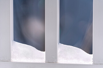 Snow collects between slats of a vinyl fence on a cold winter morning.