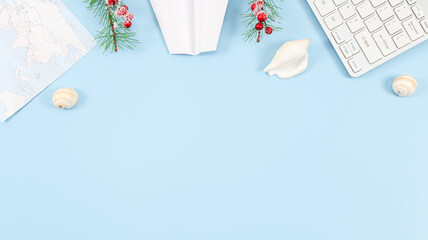 Keyboard, world map, seashells, paper plane and fir branches with red berries on a light blue