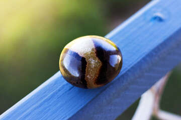 circular septarian stone resting on a blue surface with sunlight in the background.