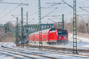 Fototapeta na wymiar Red train runs on the tracks covered by snow