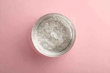 Jar of cosmetic gel on pink background, top view