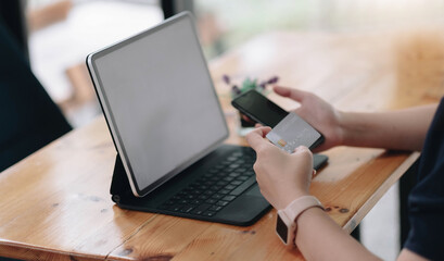 Fototapeta premium Online payment, Women's hands holding a credit card and using smartphone and choose some product what her want for online shopping.