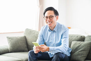 部屋でスマホを見る男性