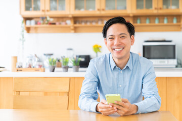 部屋でスマホを見る男性