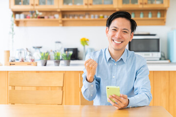 部屋でスマホを見る男性