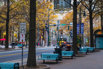a gorgeous shot of an autumn landscape in the city with rows of blue benches surrounded by gorgeous...