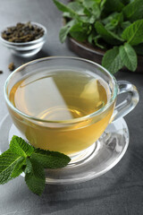 Cup of hot aromatic mint tea on grey table