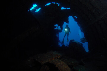 Scuba diver looks inside sunken ship.