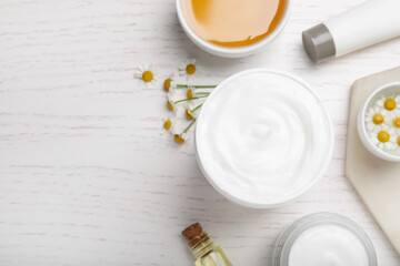Fototapeta na wymiar Body cream and other cosmetics, honey with camomile on white wooden table, flat lay. Space for text
