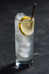 tom collins tall glass with lemon wheel and gold drinking straw