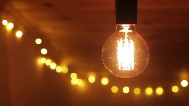 Retro light bulb flickering on a wooden ceiling, close up
