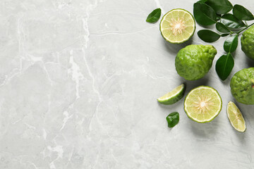 Fresh ripe bergamot fruits with green leaves on light grey marble table, flat lay. Space for text - obrazy, fototapety, plakaty