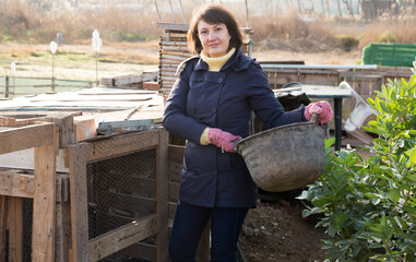 Portrait of young female amateur gardener standing near henhouse in homestead