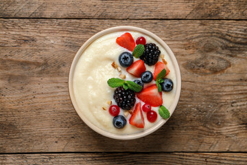 Delicious semolina pudding with berries on wooden table, top view