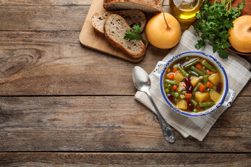 Bowl of tasty turnip soup with bread and ingredients on wooden table, flat lay. Space for text