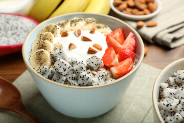 Bowl of granola with pitahaya, banana, strawberries and yogurt on table