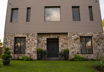 Architecture. Steel framing construction. Modern house in the suburbs at sunset. The green grass, front yard and house facade with a beautiful dusk light.