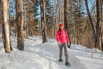 Winter snowshoe hiking people. Snowshoeing asian multiracial woman in winter forest on hike in snow wearing snowshoes living healthy active outdoor lifestyle