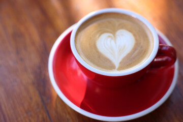 Cup of aromatic coffee with foam on wooden table, closeup. Space for text