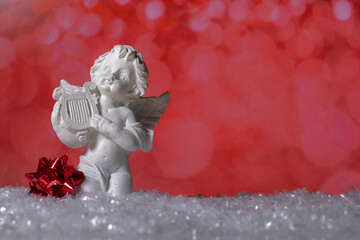 Ceramic angel statue and christmas decor standing on snow 