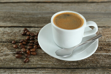 Cup of tasty coffee and beans on wooden table