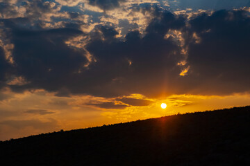 Beautiful golden orange sunset with horison silhouette and sun beams shining through clouds for concept design.