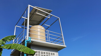 Water tank on the tower with solar panels. Close up water tank with solar panels on top for pumping...