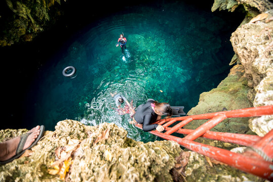 A female diver descends the ladder into Cabugnaw Cave, in Anda, Bohol, Philippines.