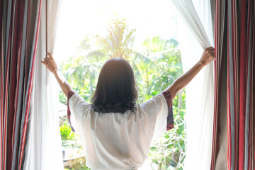 Morning of a new day, alarm clock wake up woman sitting in the room. A woman stretch the muscles at window. Health and care concepts