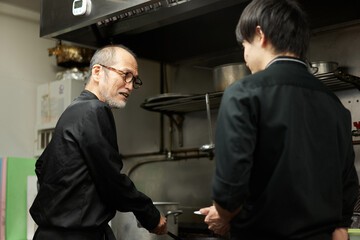レストランで仕事を教えるアジア人のスタッフ