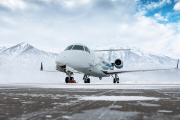 Luxury corporate business jet on the winter airport apron on the background of high scenic mountains