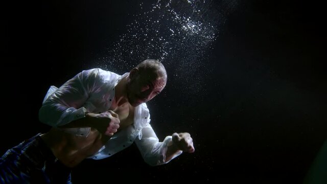 amazing underwater shot of fighting man, muscular fighter in white unfastened shirt