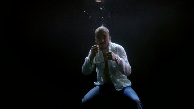 dark depth of sea or ocean, figure of boxing man, brave agressive boxer is swaying hands
