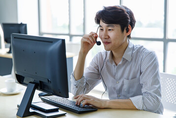 Asian happy male corporate receptionist operator service support employee staff wearing headset adjusting microphone when discussing talking helping having conversation with clients customers online