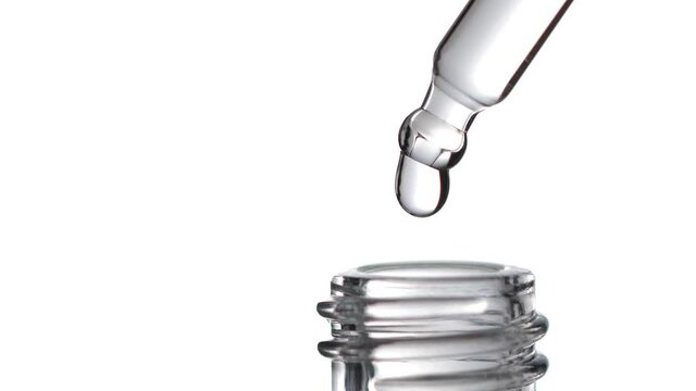 Drop of water falling from glass lab pipette in bottle isolated on white background. Macro