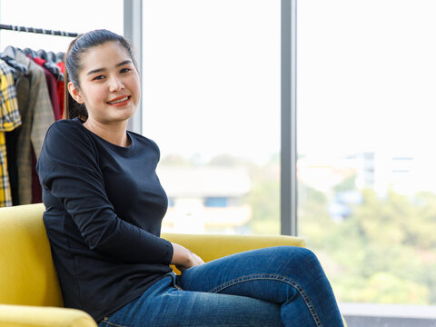 Asian young happy cheerful millennial successful female blogger vlogger businesswoman influenzer in casual outfit sit smiling laughing in home studio store selling clothes online via laptop computer